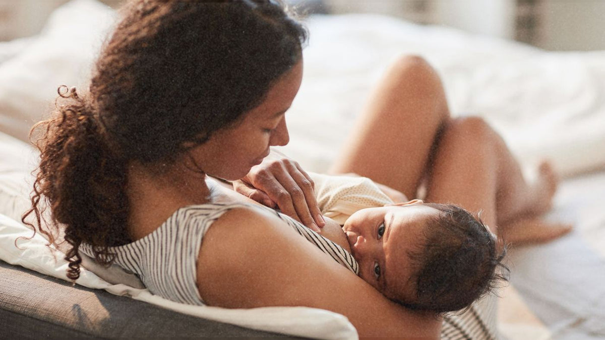 A parent breastfeeding their baby in bed