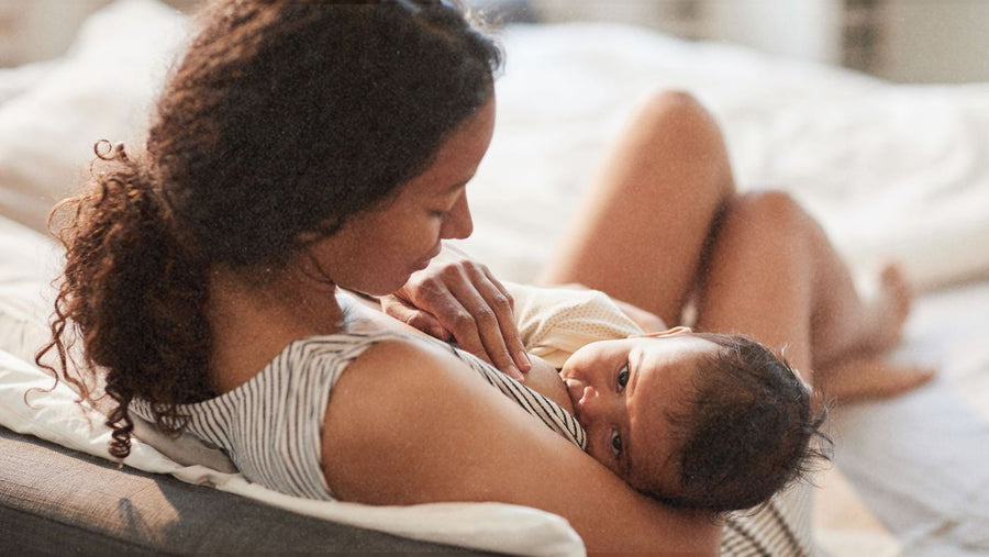 A parent breastfeeding their baby in bed